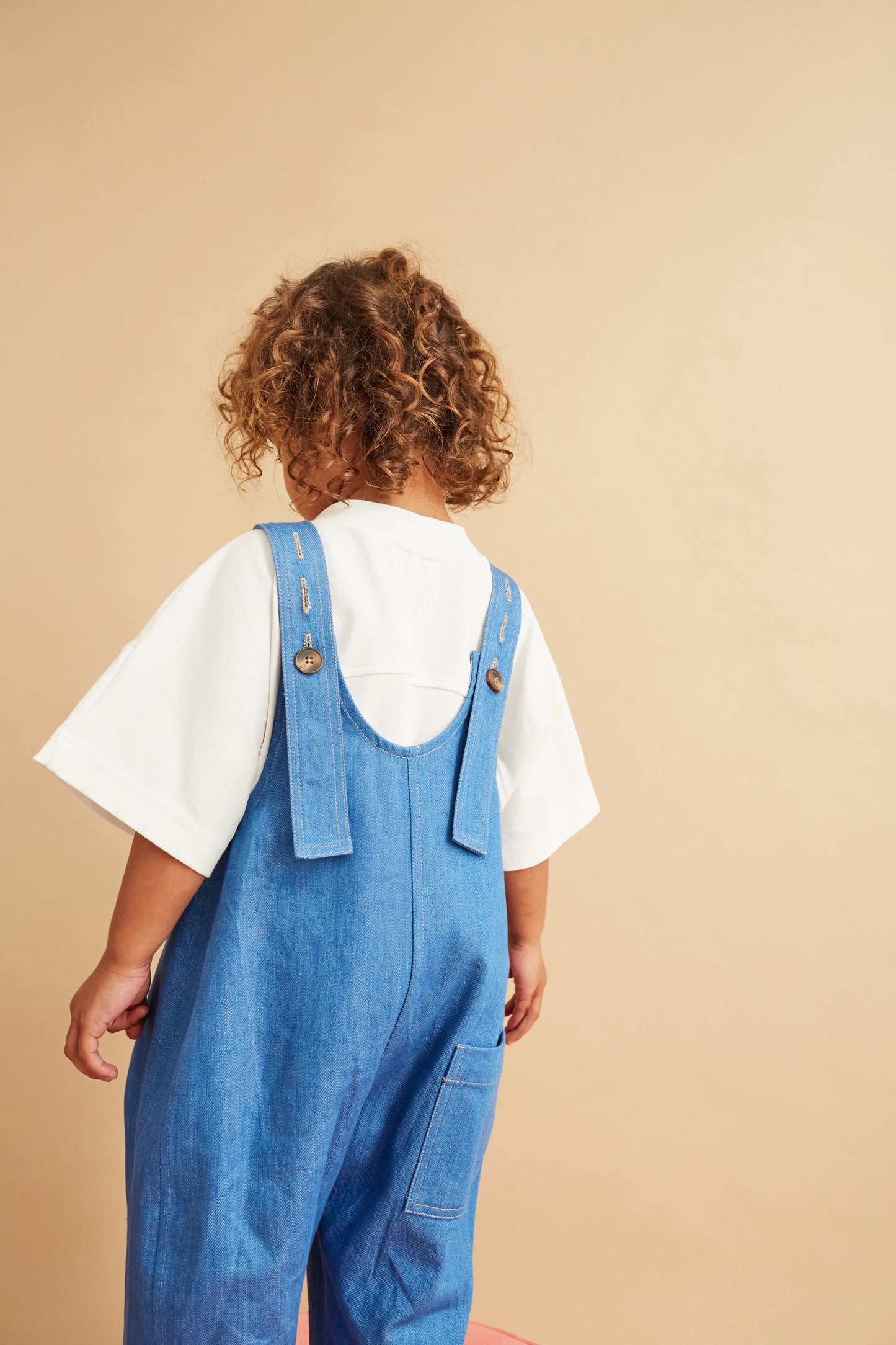 Studio Koter Kai Denim Dungarees front view showing oversized fit and curved seam details on sustainable kids clothing