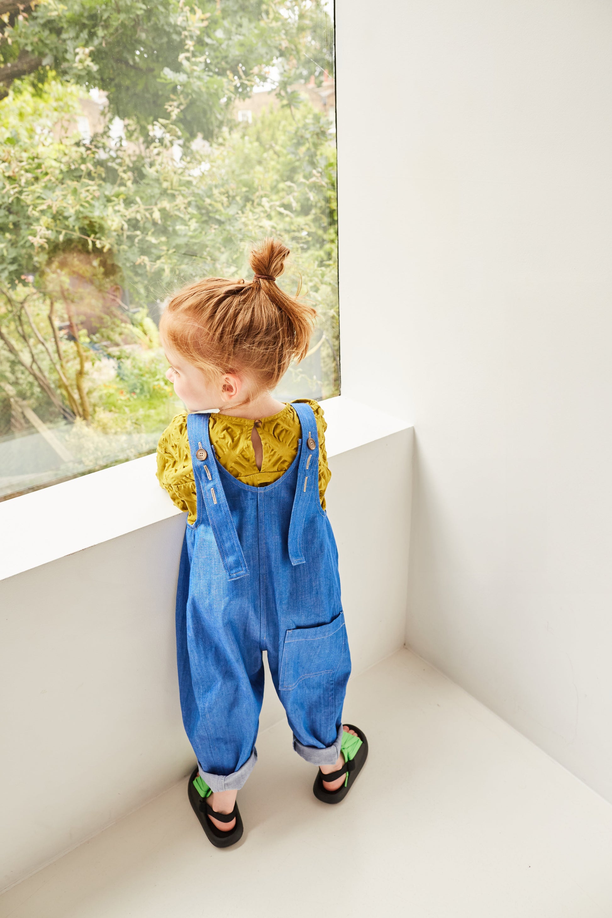 Back view of Kai organic cotton dungarees featuring utility pockets and adjustable straps